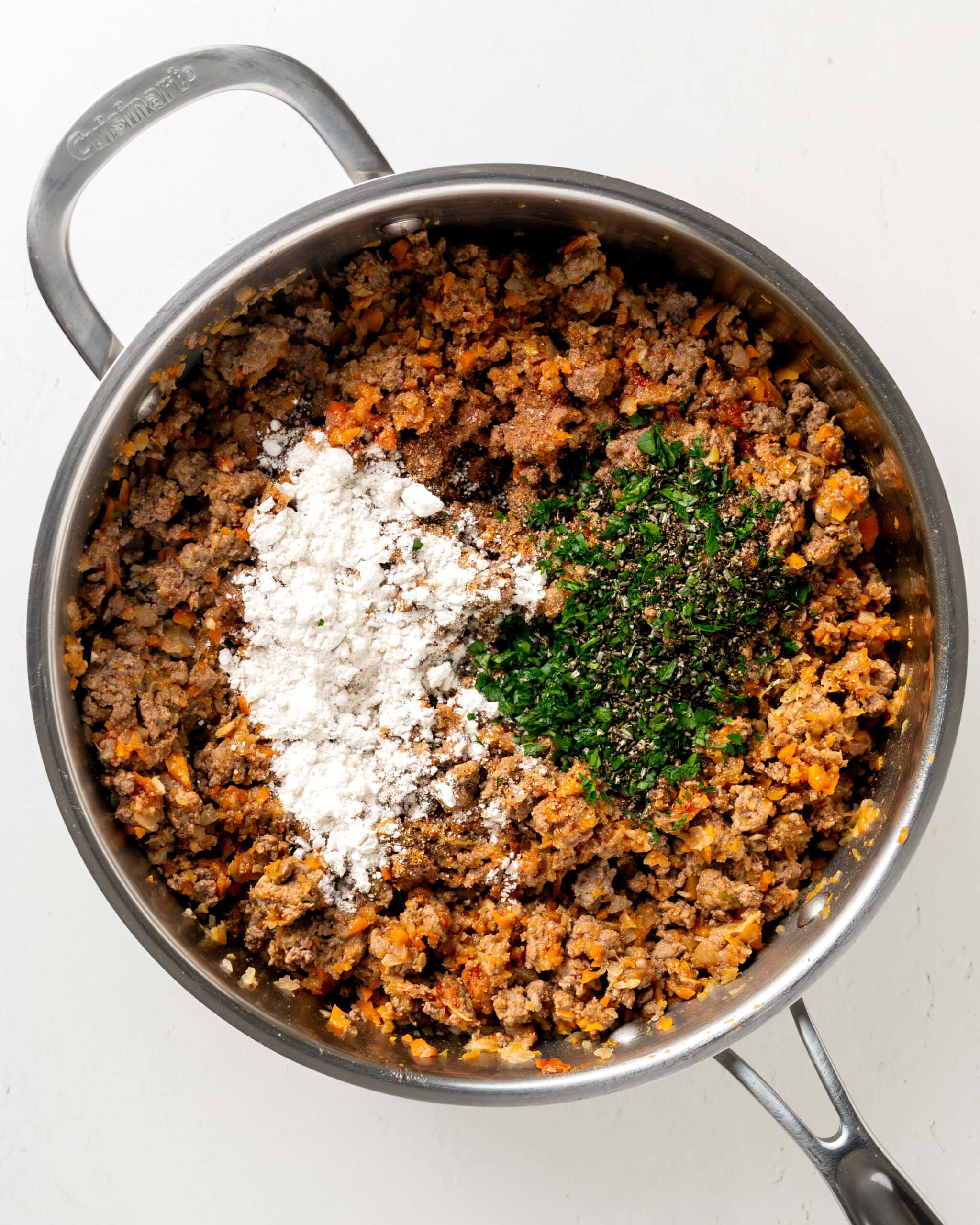 Adding gluten free flour and herbs to lamb mixture.