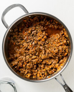 Adding beef broth to lamb mixture.