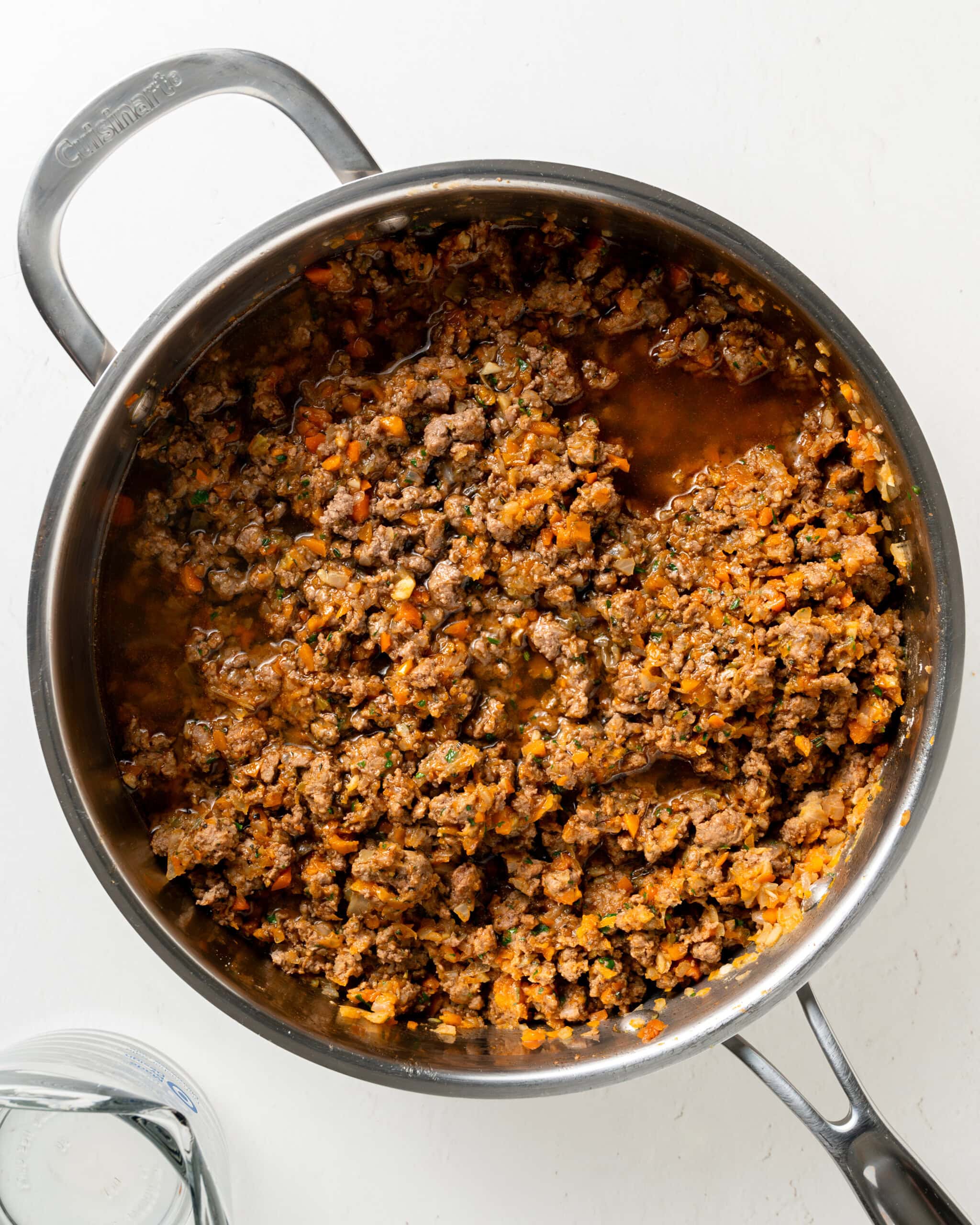 Adding beef broth to lamb mixture.