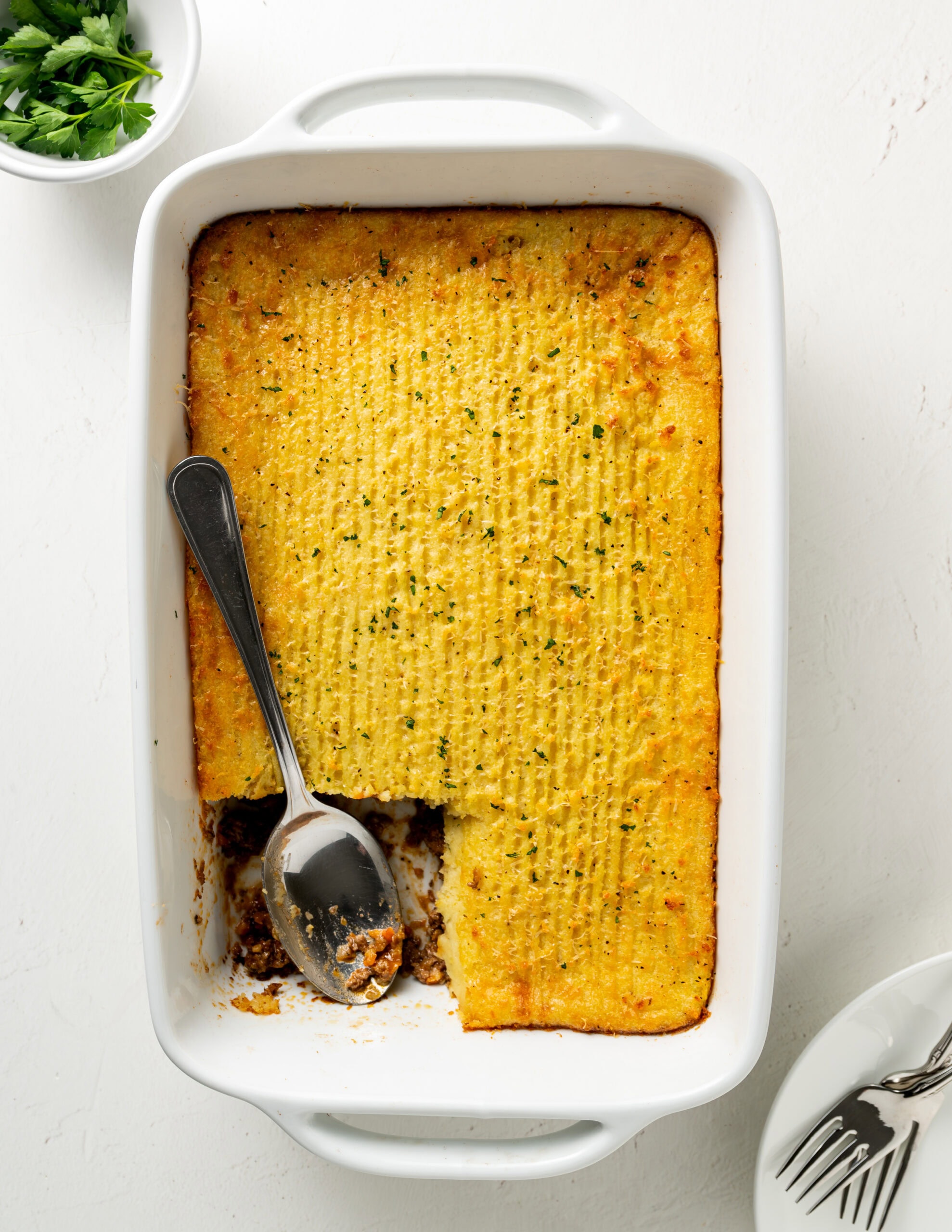 Overhead shot over gluten free shepherd's pie in a casserole dish with a spoon exposing the lamb and veggies, 