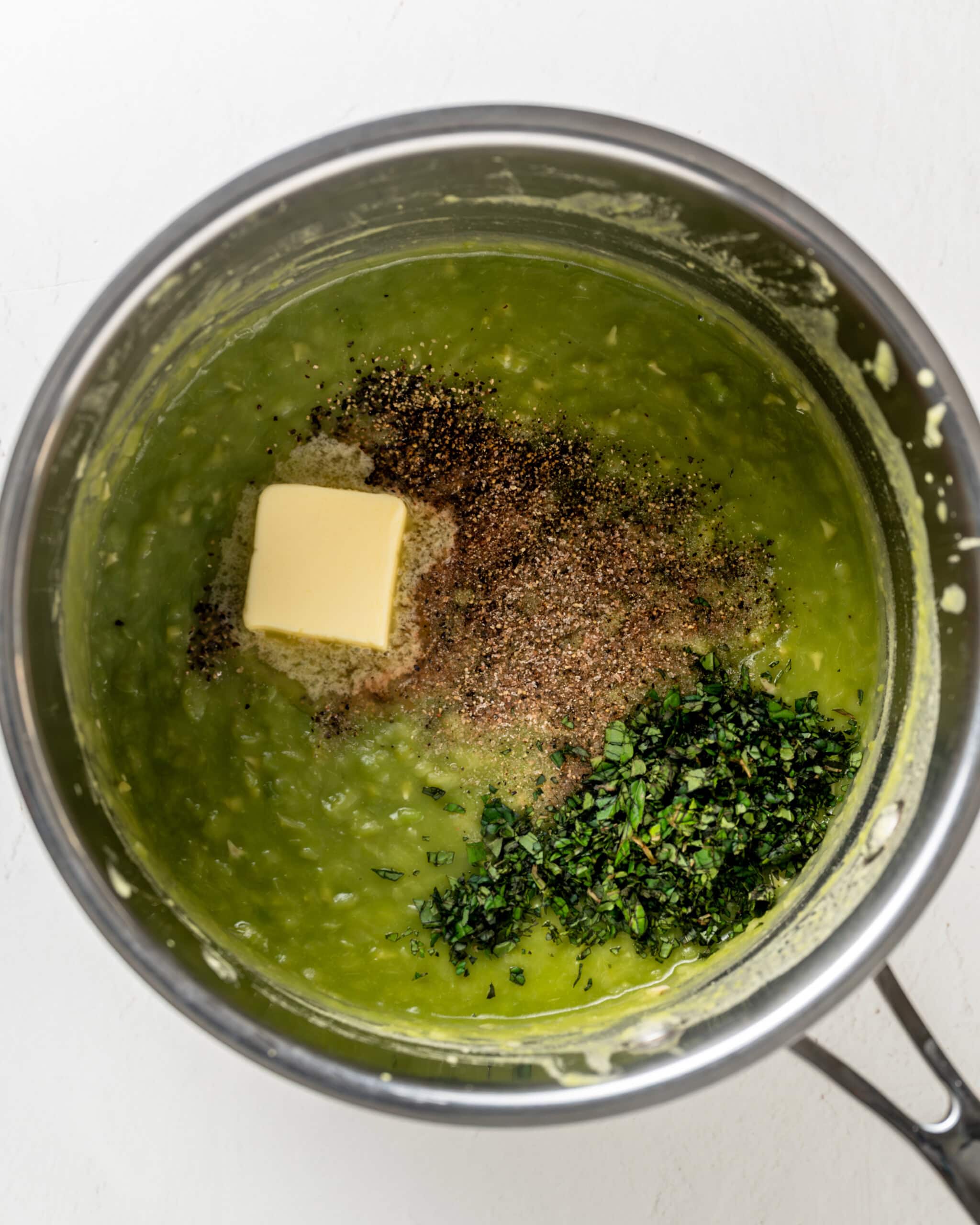 Adding butter, seasonings, and herbs to mushy peas.