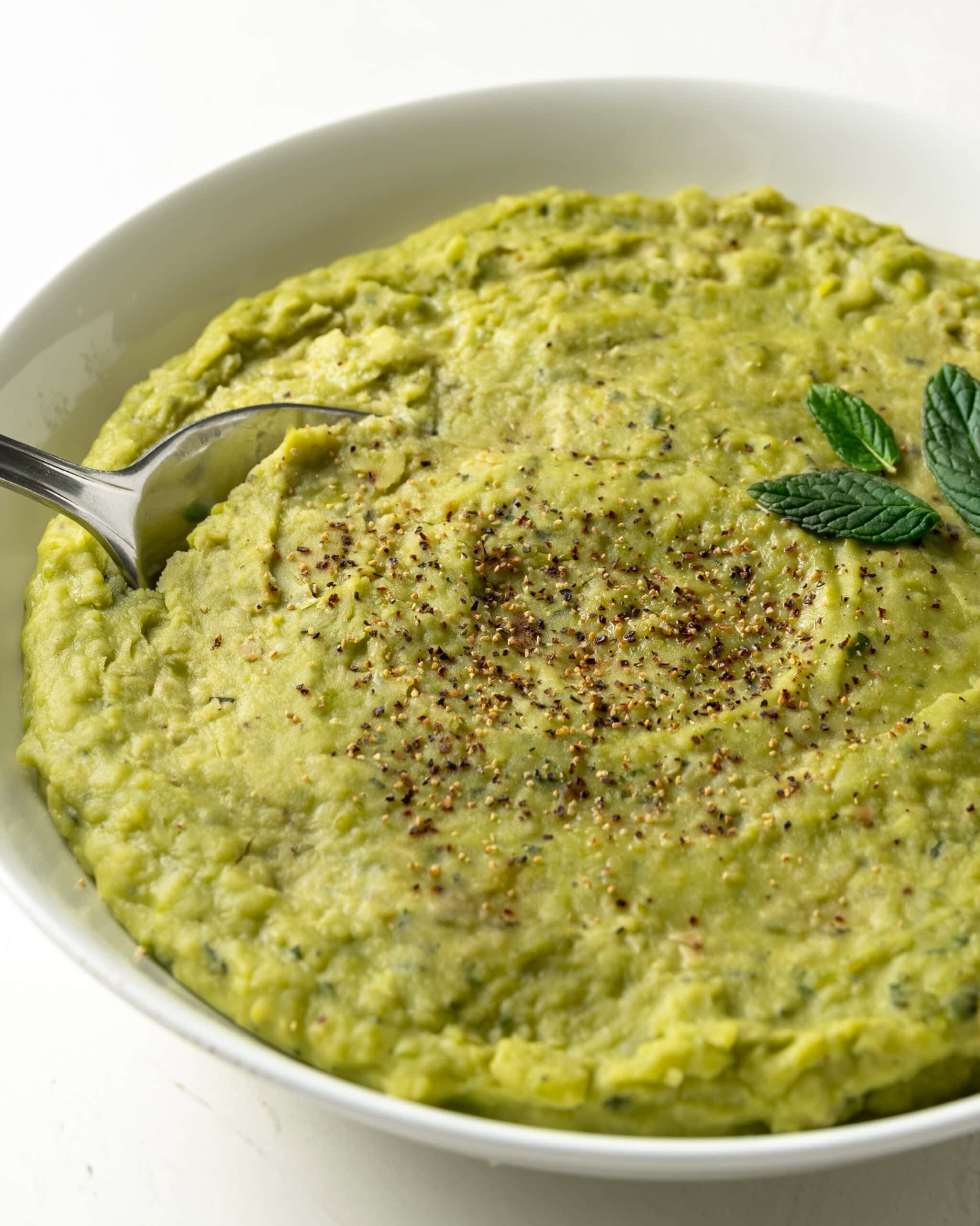 Side view of mushy peas with black pepper on top.