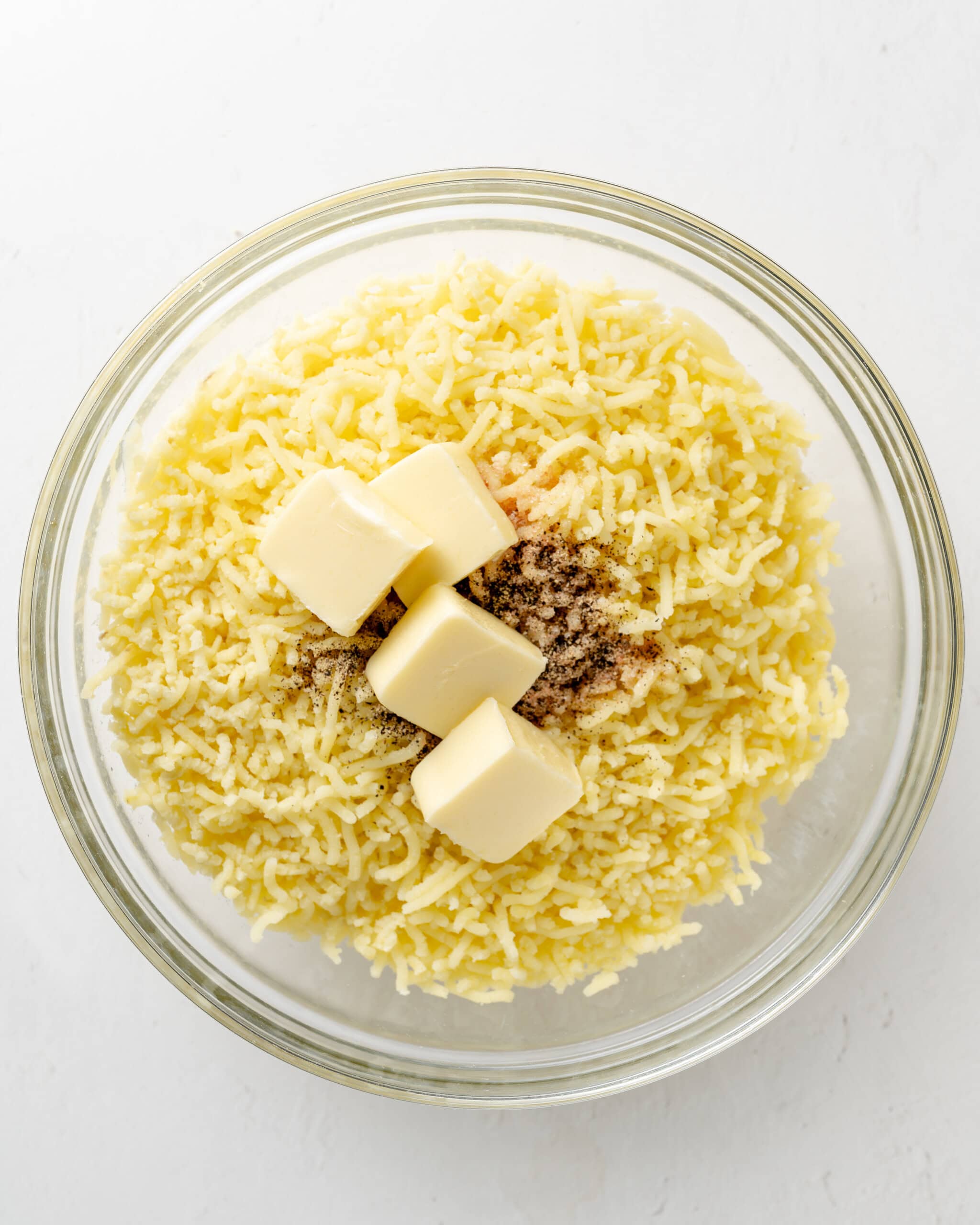 Adding butter and seasoning to riced potatoes