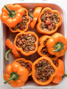 Placing the stuffed peppers in a baking dish with the top of the pepper lids.