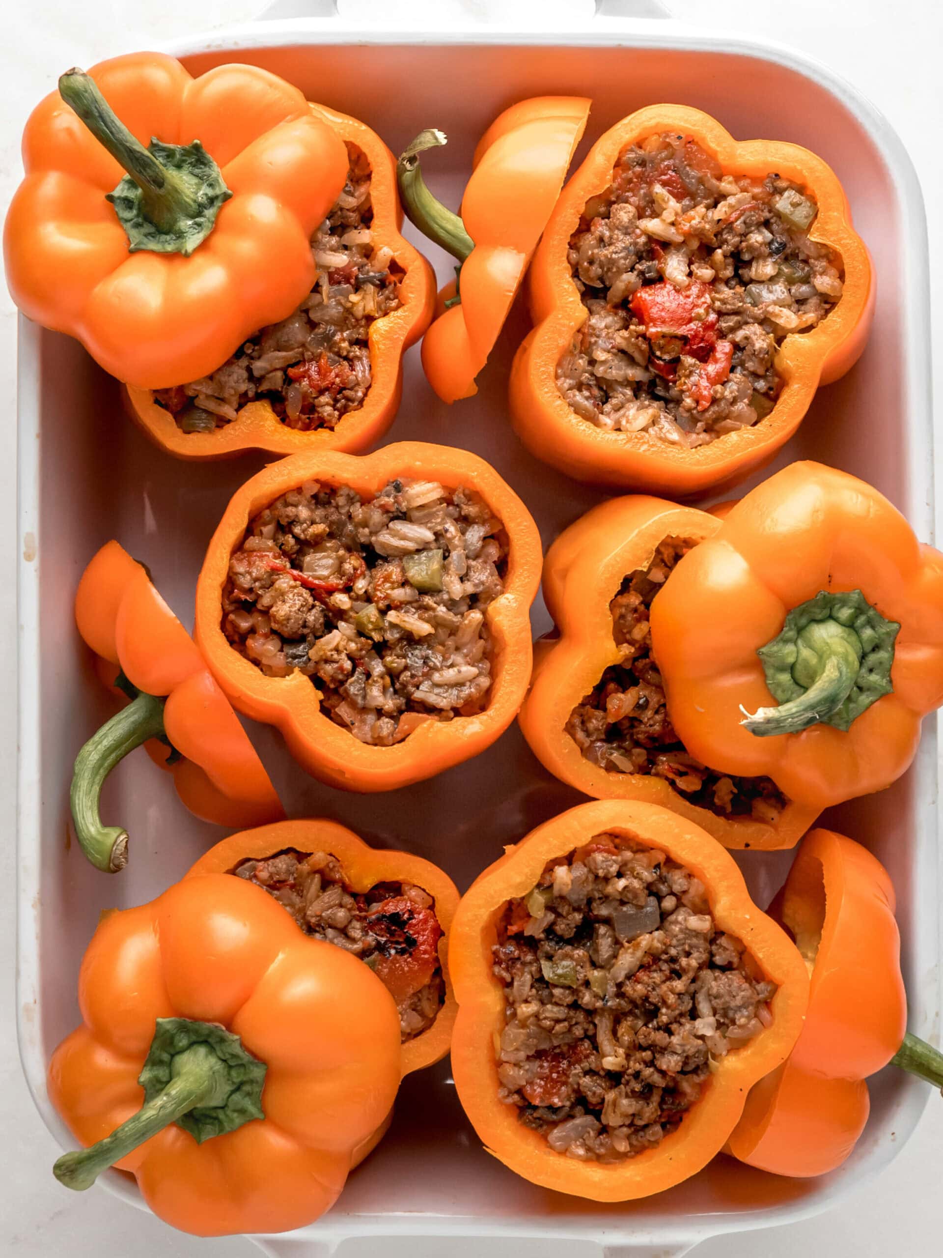 Stuffing the peppers with the beef and rice mixture, then placing them in a large baking dish.