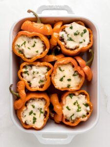 Adding cheese to the tops of the baked stuffed peppers and baking them until the cheese is melted.