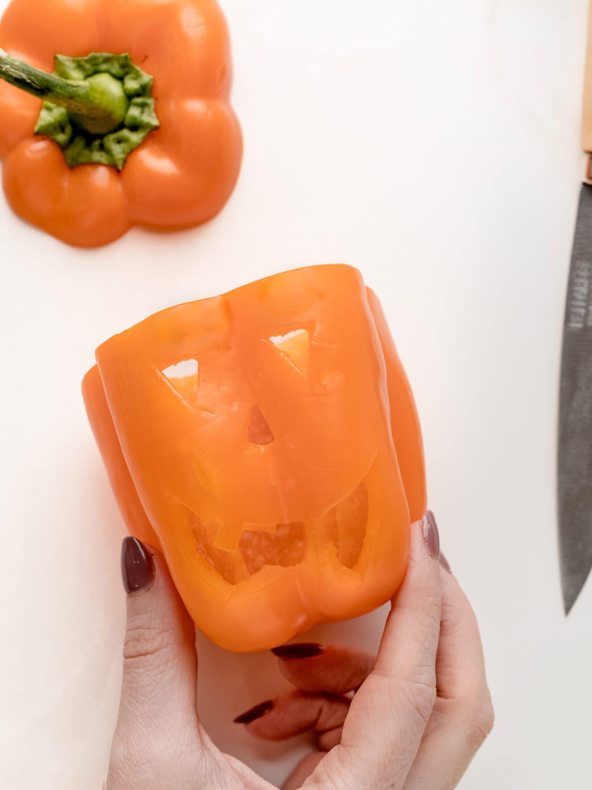 Carving out the faces of the stuffed pepper.