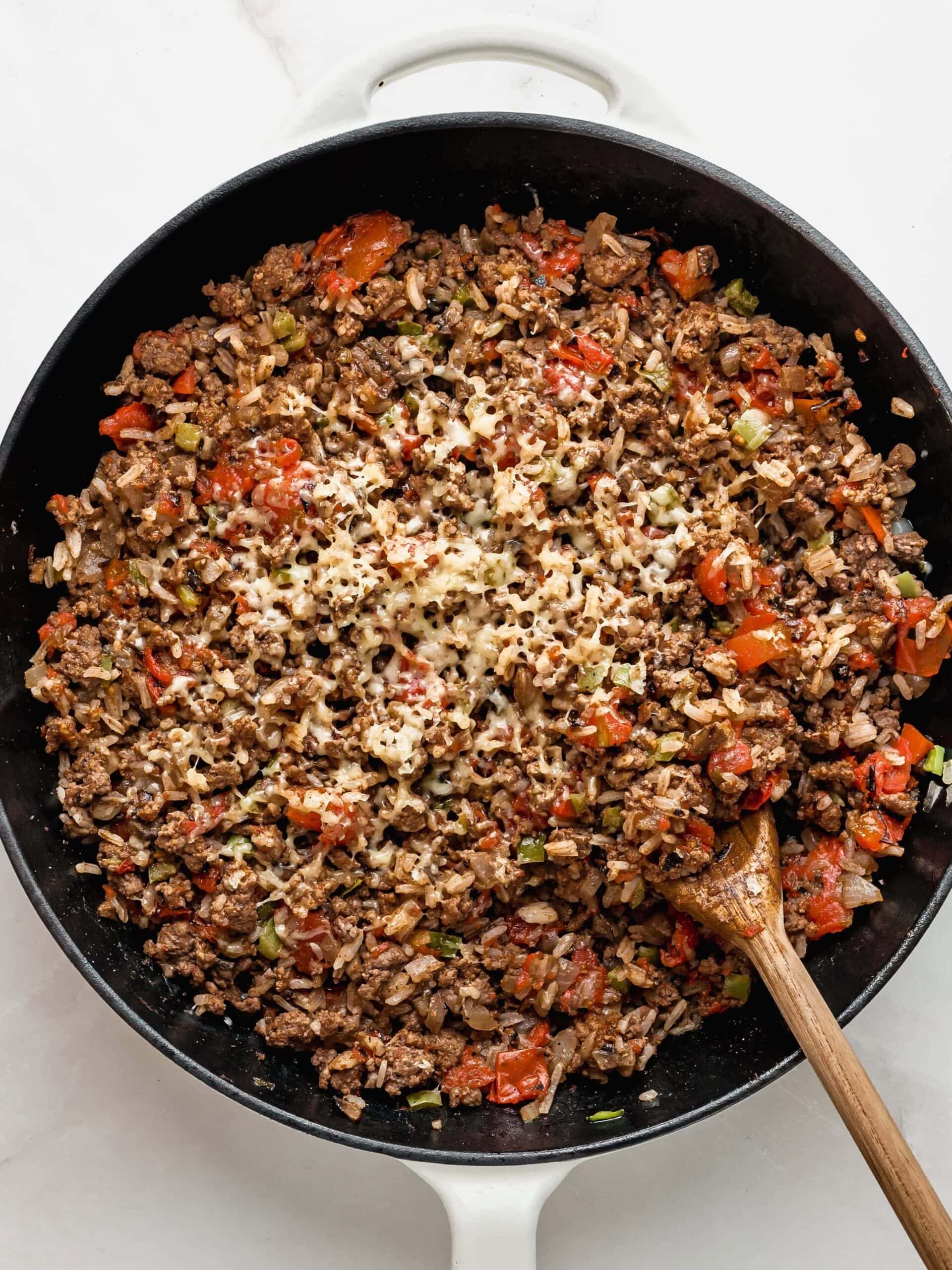 Adding rice, tomatoes, and cheese to the stuffed pepper filling.