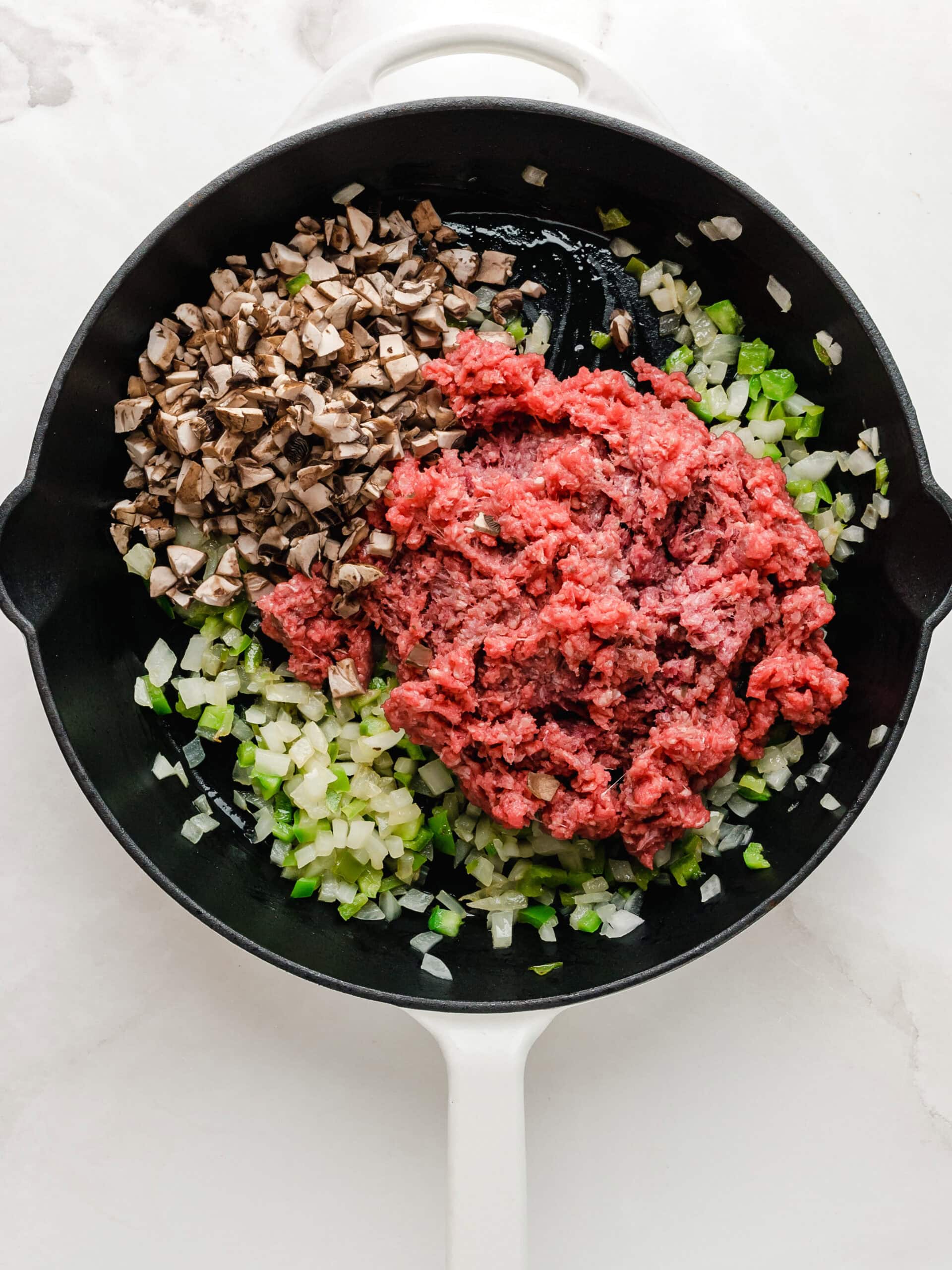 Sauteed vegetables and browning the ground beef in a large skillet.
